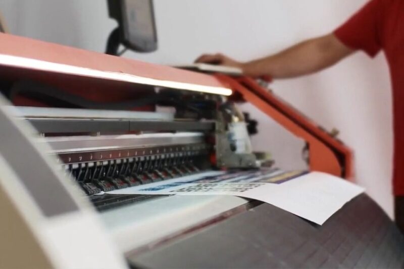 Veliki štamparski uređaj štampa list papira u profesionalnom okruženju